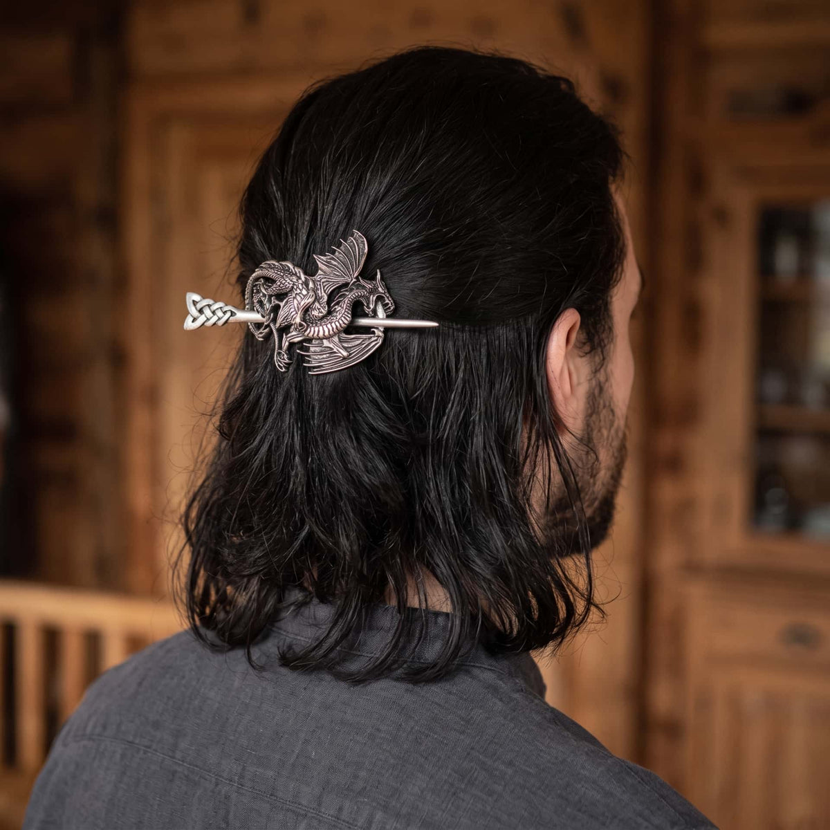 Femme de dos, cheveux tressés tenus par une barrette viking à dragon ailé