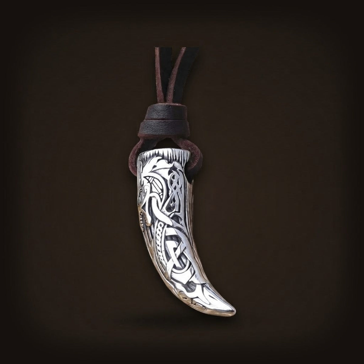Pendentif viking en forme de dent de loup avec gravures d'entrelacs nordiques sur lanière en cuir brun.