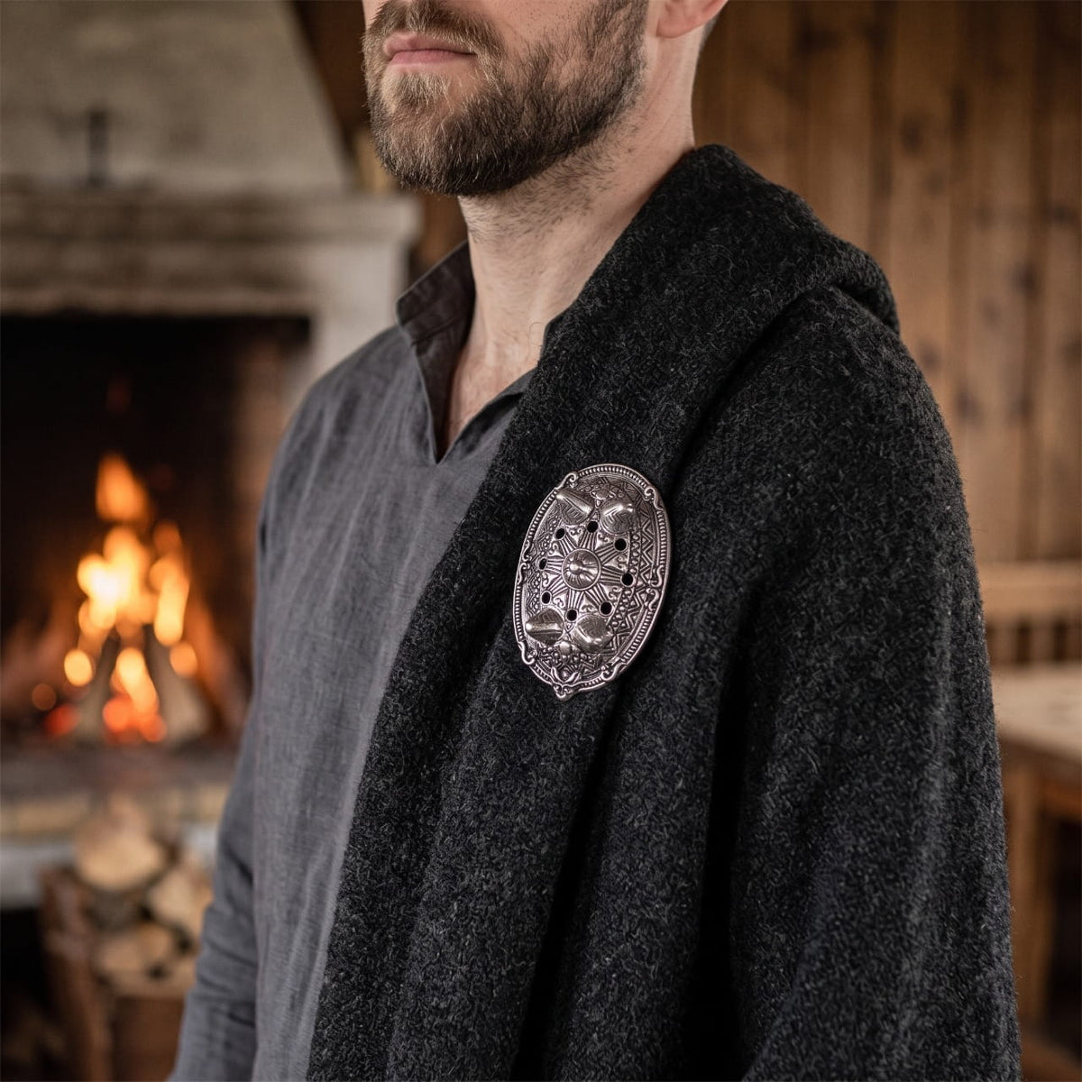 Homme portant une fibule viking ovale bombée en argent vieilli sur une cape de laine grise