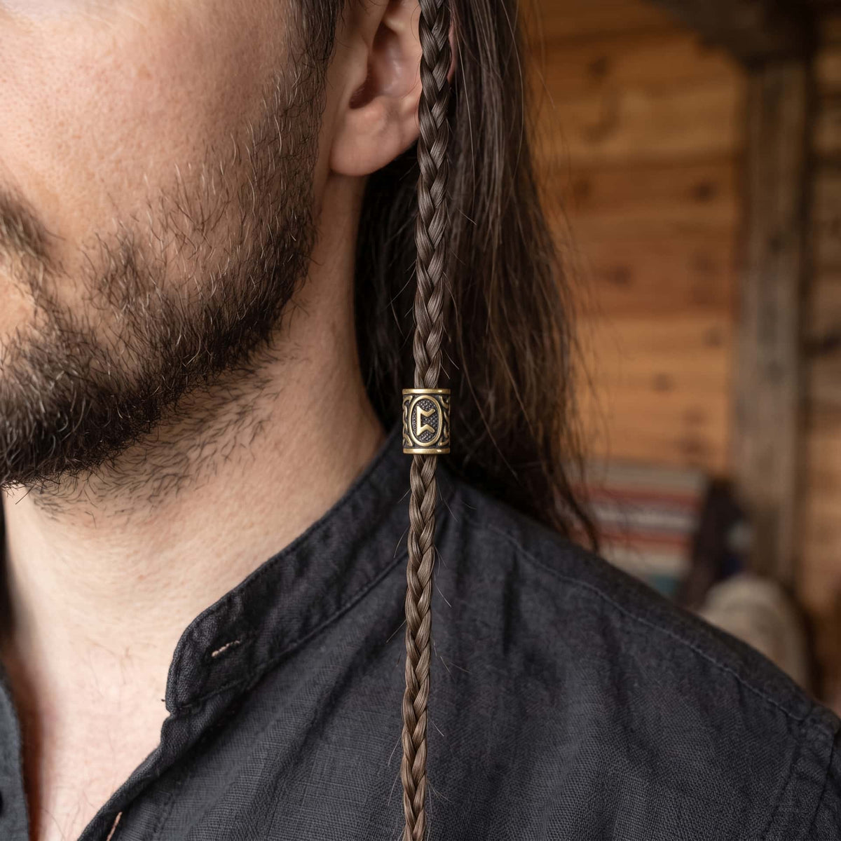 Perle viking en alliage bronze patiné, gravée de la rune Perthro dans un cartouche ovale, portée sur une fine tresse de cheveux