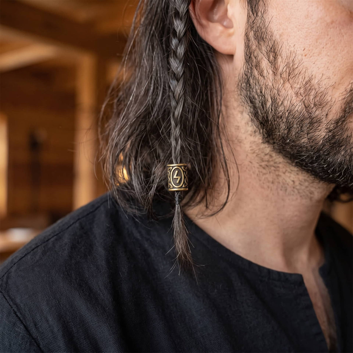 Perle viking en alliage bronze patiné, gravée de la rune Sowilo dans un cartouche ovale, portée sur une fine tresse de cheveux