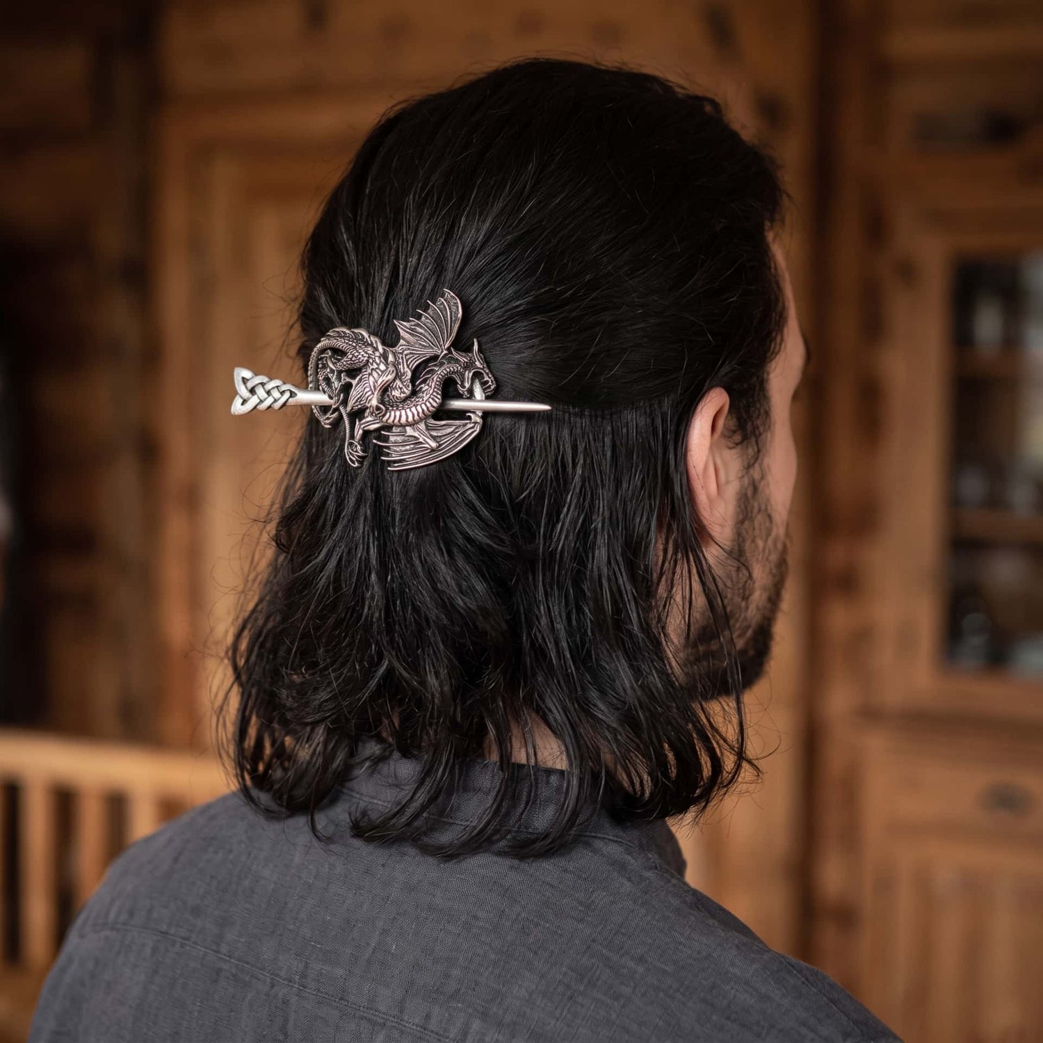 Femme de dos, cheveux tressés tenus par une barrette viking à dragon ailé