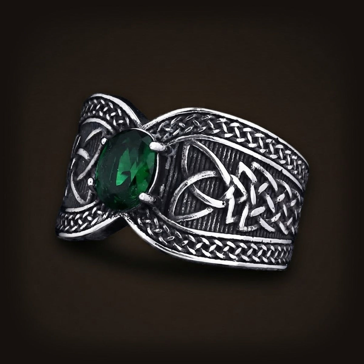 Bague large en acier patiné couverte de triquetras et de bordures tressées, sertie d'un zircon vert