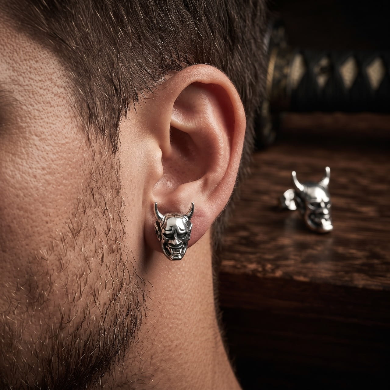 Puce d'oreille crâne cornu en acier portée au lobe d'un homme barbu