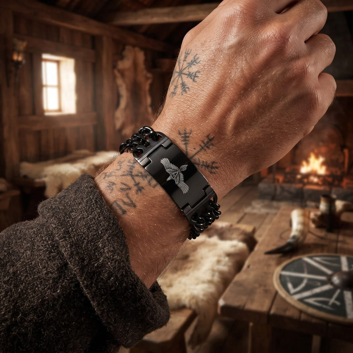 Bracelet viking en acier noirci à plaque gravée, porté au poignet dans une maison longue viking