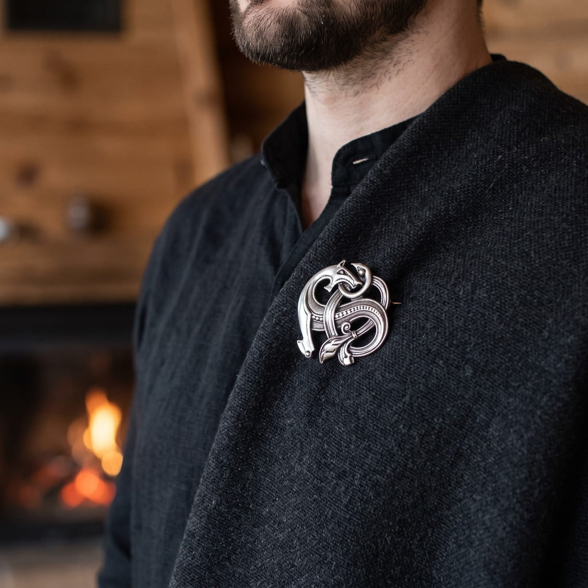 Homme portant une broche viking bête d'Urnes entrelacée en argent vieilli sur une cape de laine