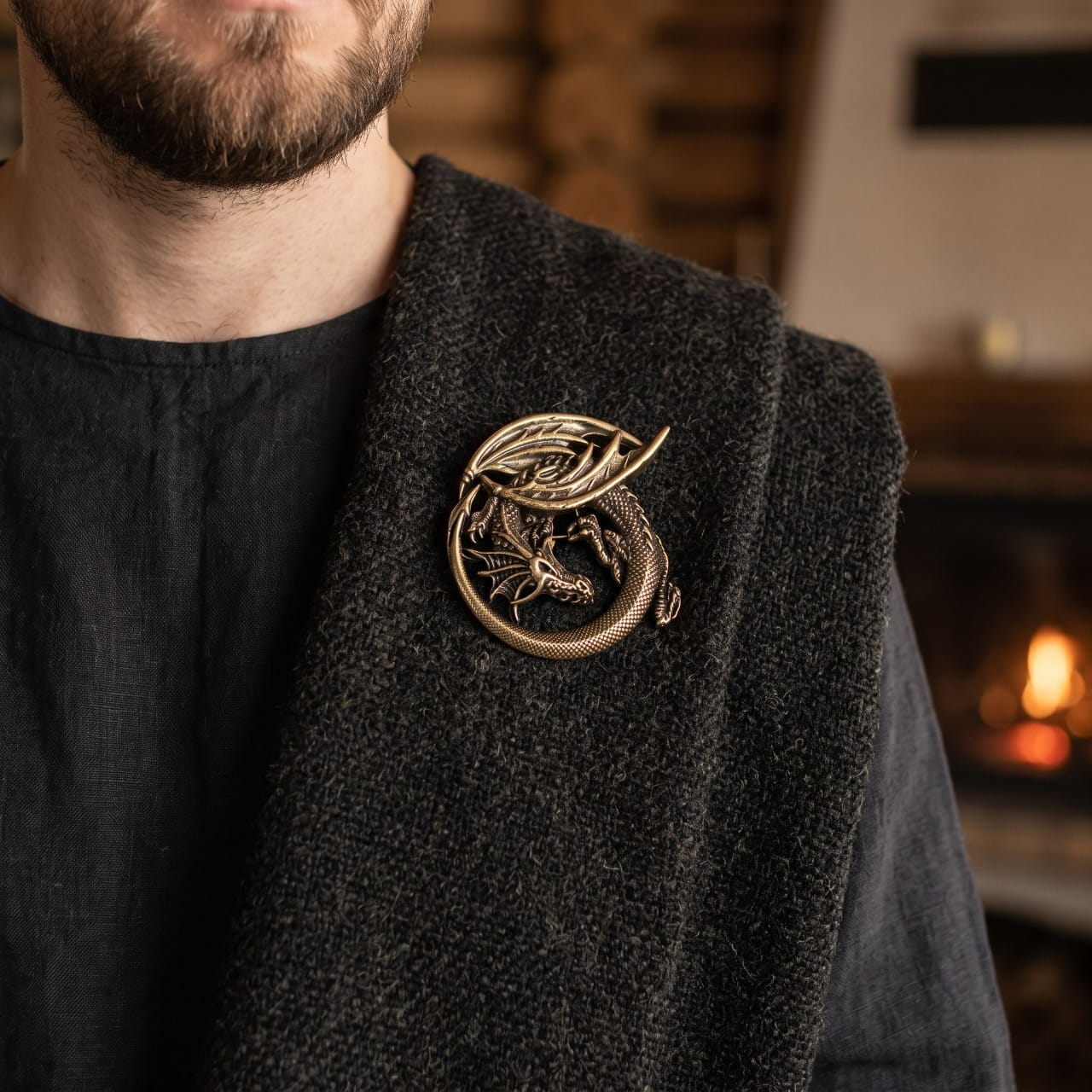 Homme portant une broche viking dragon lové en bronze sur une cape de laine sombre