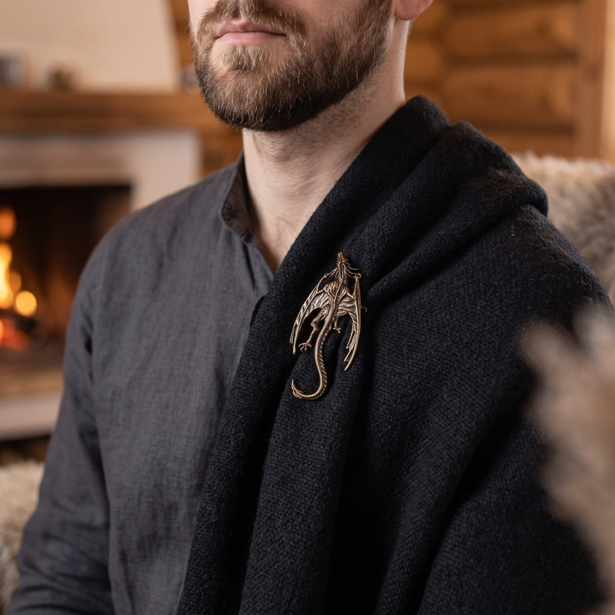 Homme portant une broche viking dragon perché en bronze sur une cape de laine sombre