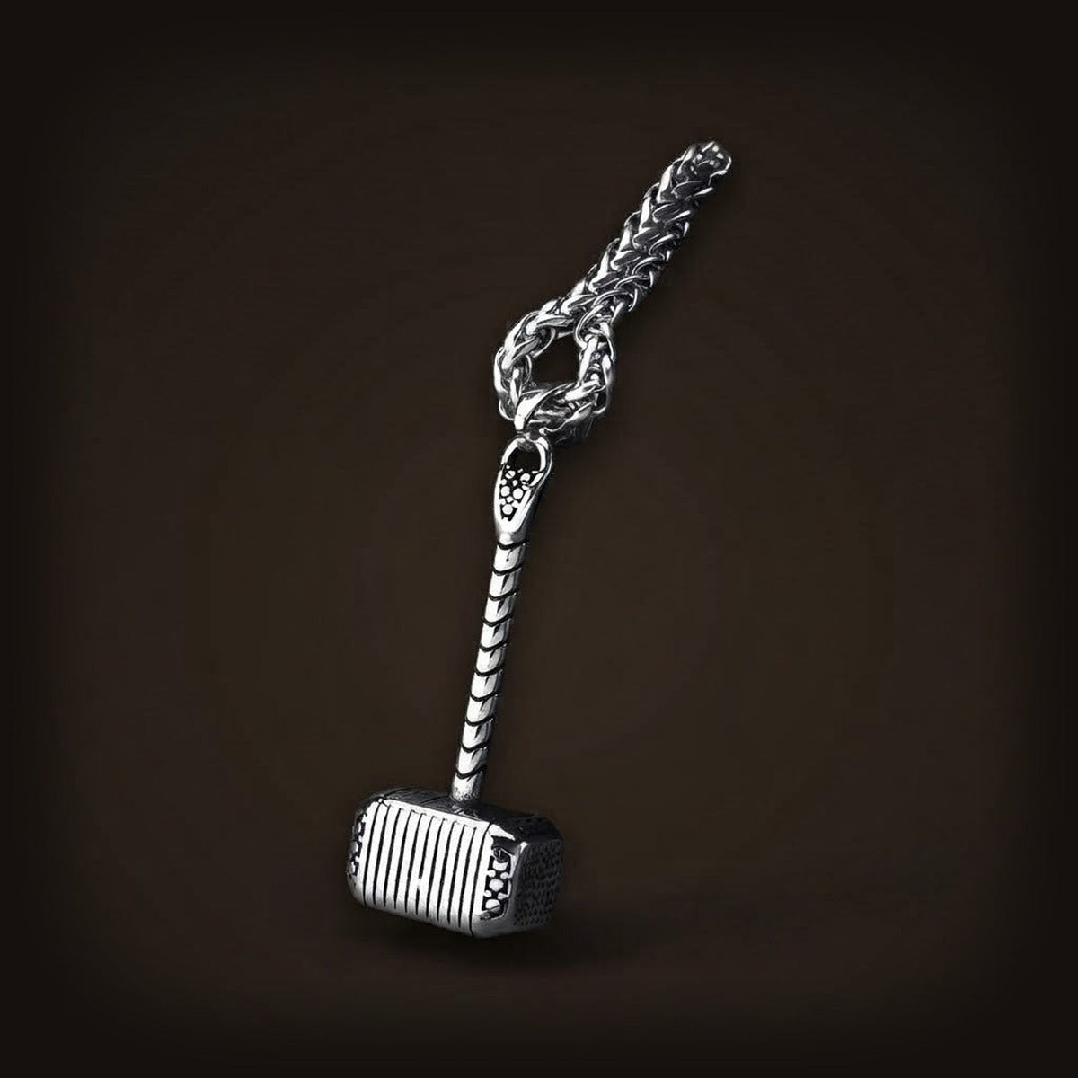 Pendentif Mjölnir en acier inoxydable, manche strié et tête gravée de motifs, avec le début de sa chaîne maille tressée