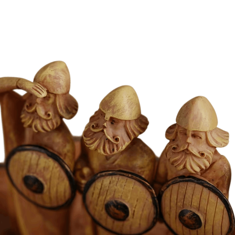Gros plan sur les trois guerriers barbus du drakkar : casques coniques dorés, barbes sculptées et boucliers ronds à umbo central.
