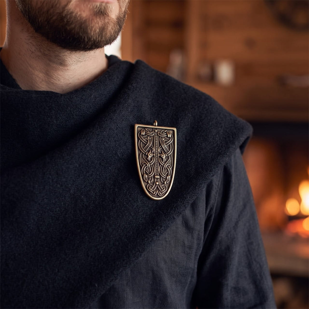 Homme portant une fibule viking en écusson à entrelacs bronze sur une cape de laine sombre