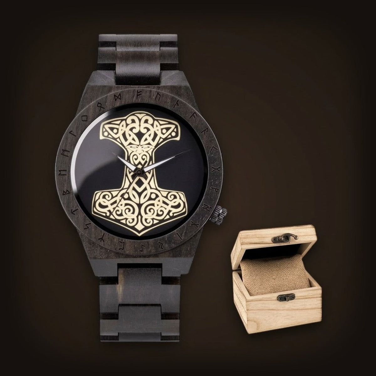Montre viking pour homme en bois de santal noir avec cadran Marteau de Thor doré et lunette runique à côté de son coffret.