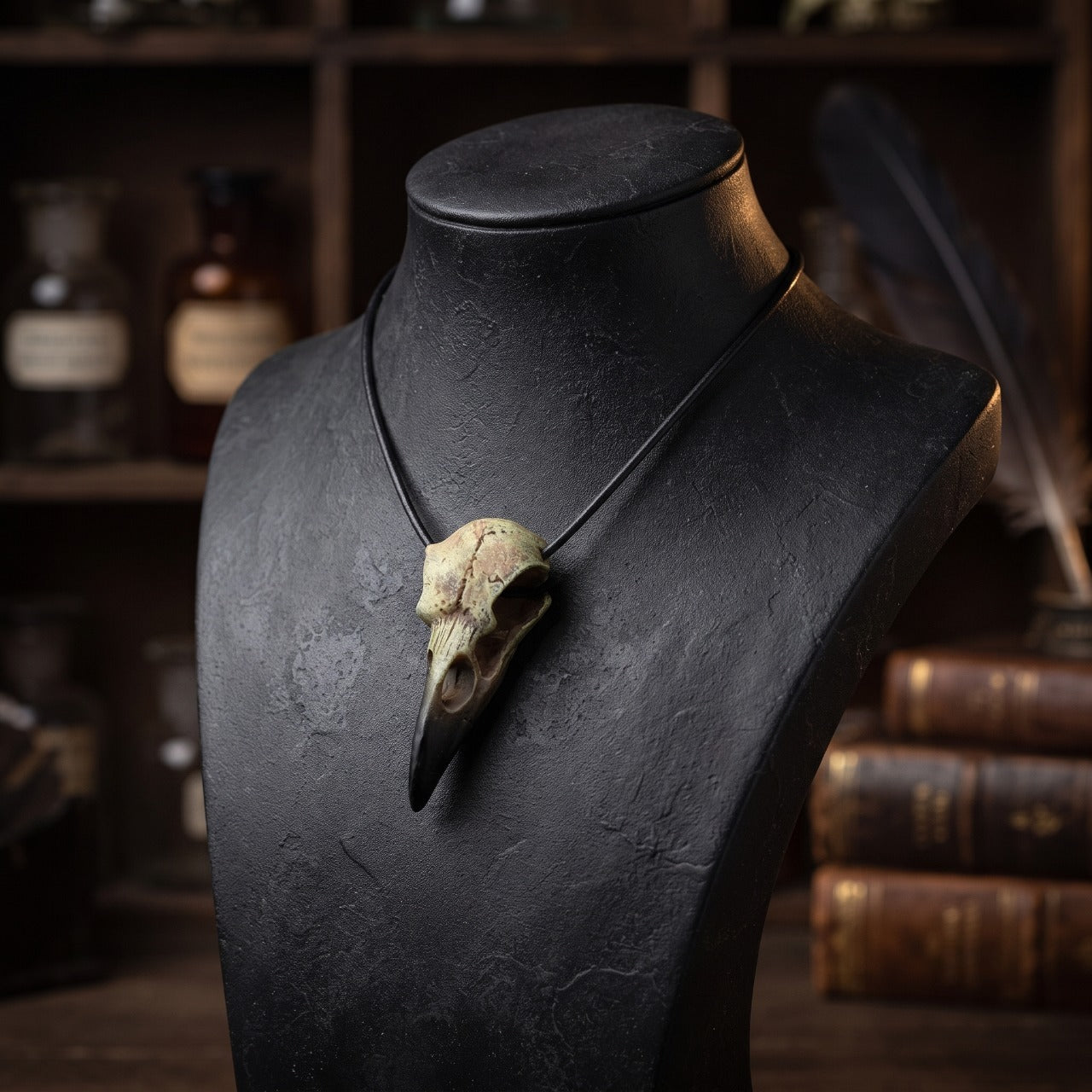 Pendentif crâne de corbeau patiné sur cordon de cuir, présenté sur un buste sombre, décor d'apothicaire