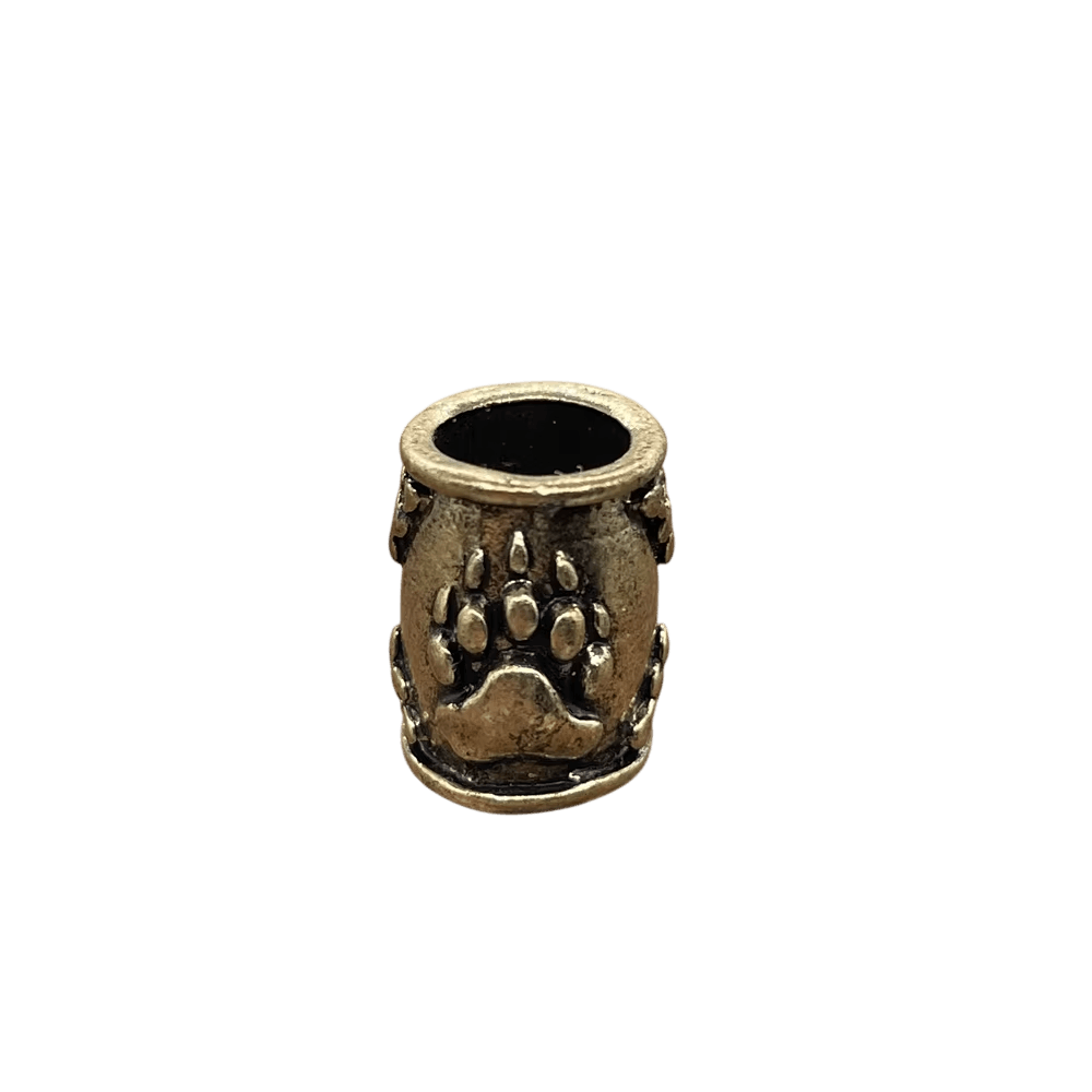 Perle viking en forme de tonneau, en alliage bronze patiné, patte d'ours en relief, perçage traversant visible, sur fond blanc