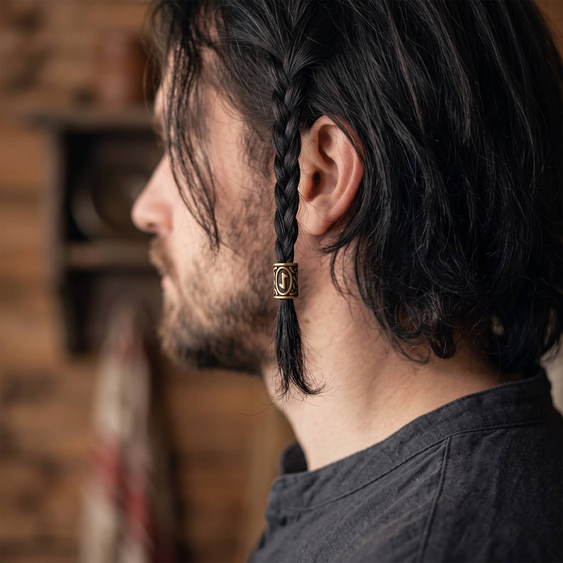 Perle viking en alliage bronze patiné, gravée de la rune Eihwaz dans un cartouche ovale, portée sur une fine tresse de cheveux