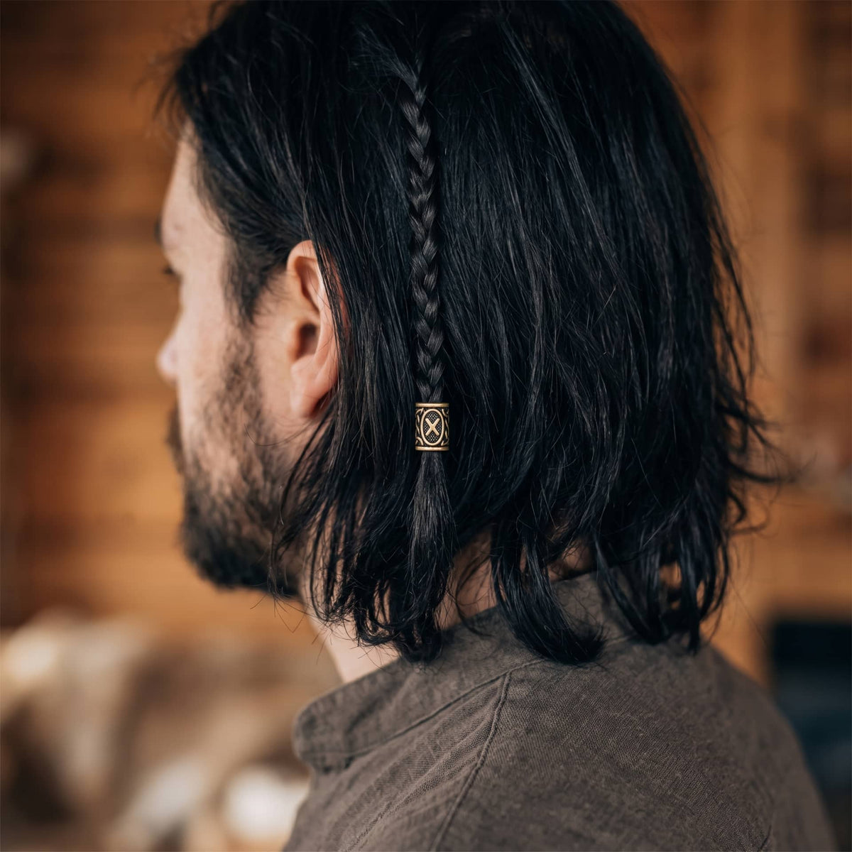 Perle viking en alliage bronze patiné, gravée de la rune Gebo dans un cartouche ovale, portée sur une fine tresse de cheveux