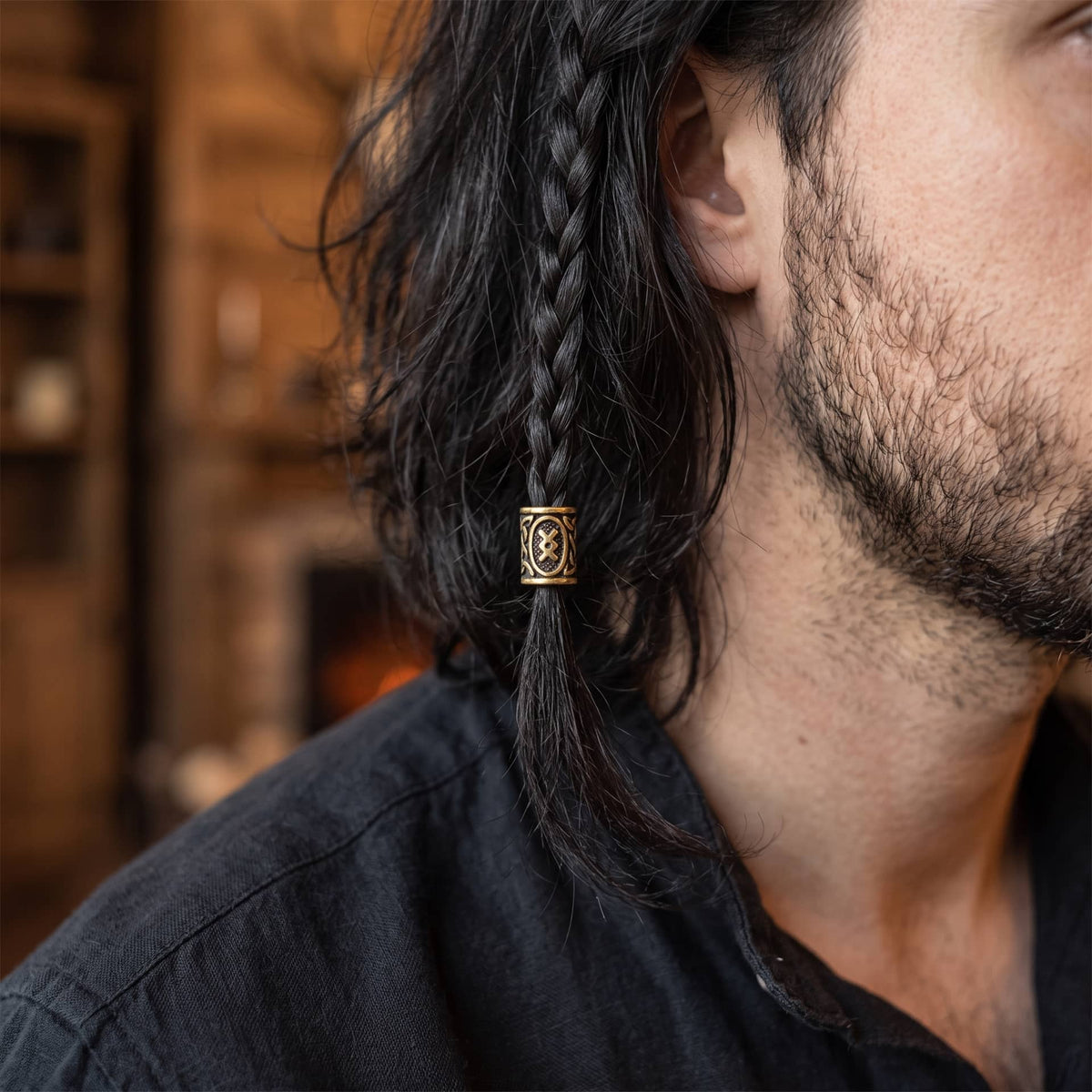Perle viking en alliage bronze patiné, gravée de la rune Ingwaz dans un cartouche ovale, portée sur une fine tresse de cheveux