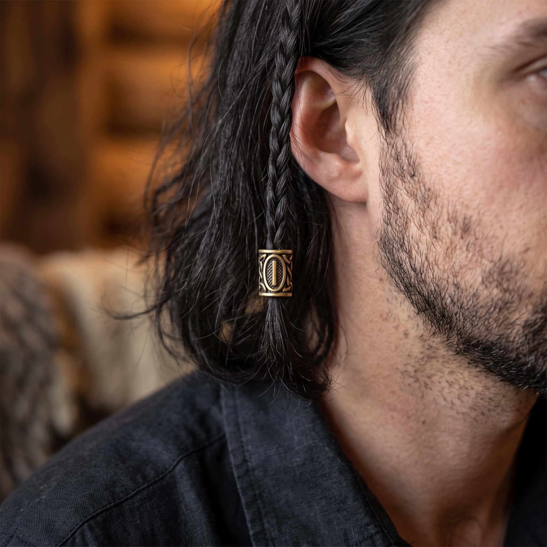 Perle viking en alliage bronze patiné, gravée de la rune Isa dans un cartouche ovale, portée sur une fine tresse de cheveux