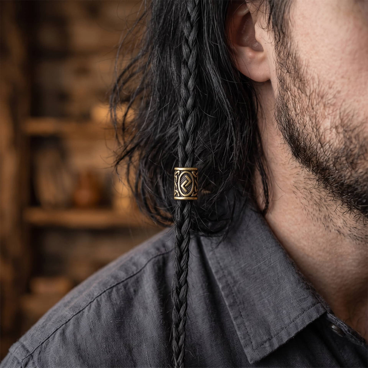 Perle viking en alliage bronze patiné, gravée de la rune Jera dans un cartouche ovale, portée sur une fine tresse de cheveux
