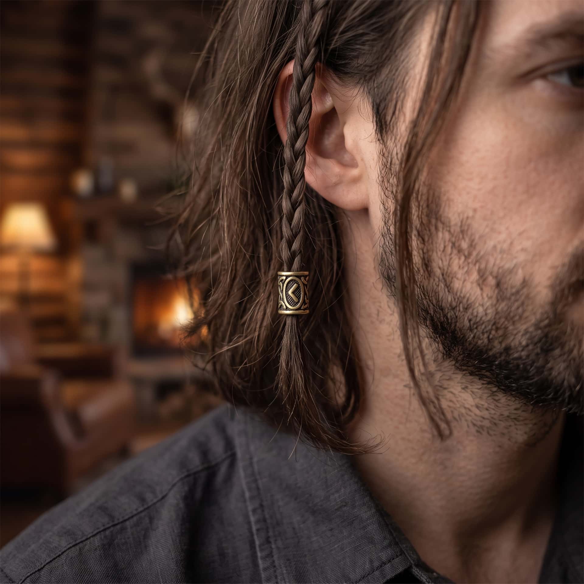 Perle viking en alliage bronze patiné, gravée de la rune Kaunaz dans un cartouche ovale, portée sur une fine tresse de cheveux