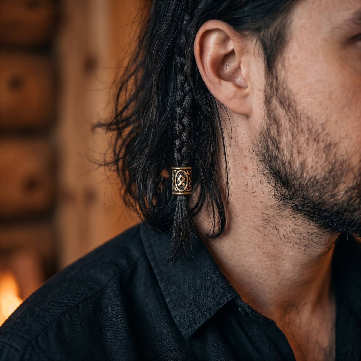 Perle viking en alliage bronze patiné, gravée de la rune Othala dans un cartouche ovale, portée sur une fine tresse de cheveux