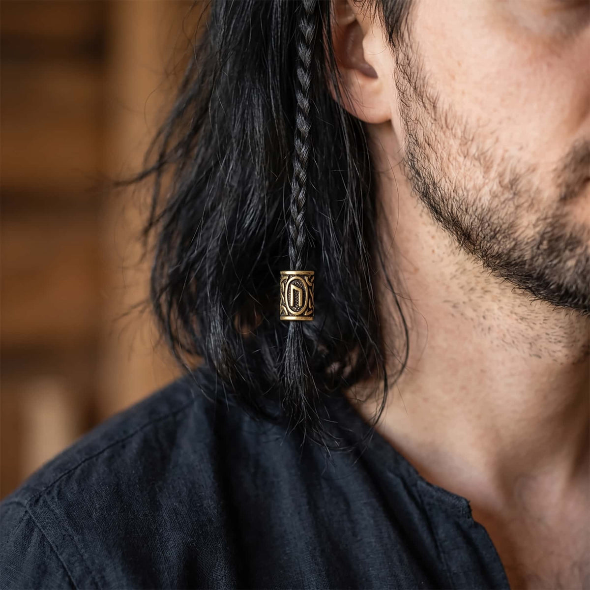 Perle viking en alliage bronze patiné, gravée de la rune Uruz dans un cartouche ovale, portée sur une fine tresse de cheveux
