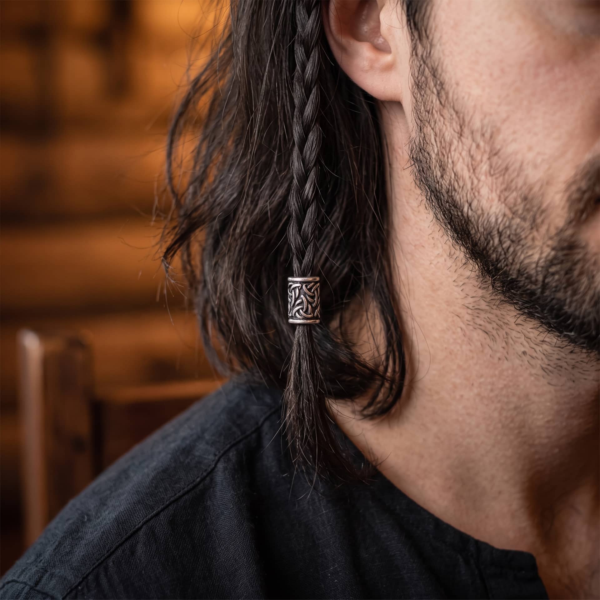 Perle viking en alliage argent vieilli, couverte d'entrelacs formant des triquetras, portée sur une fine tresse de cheveux