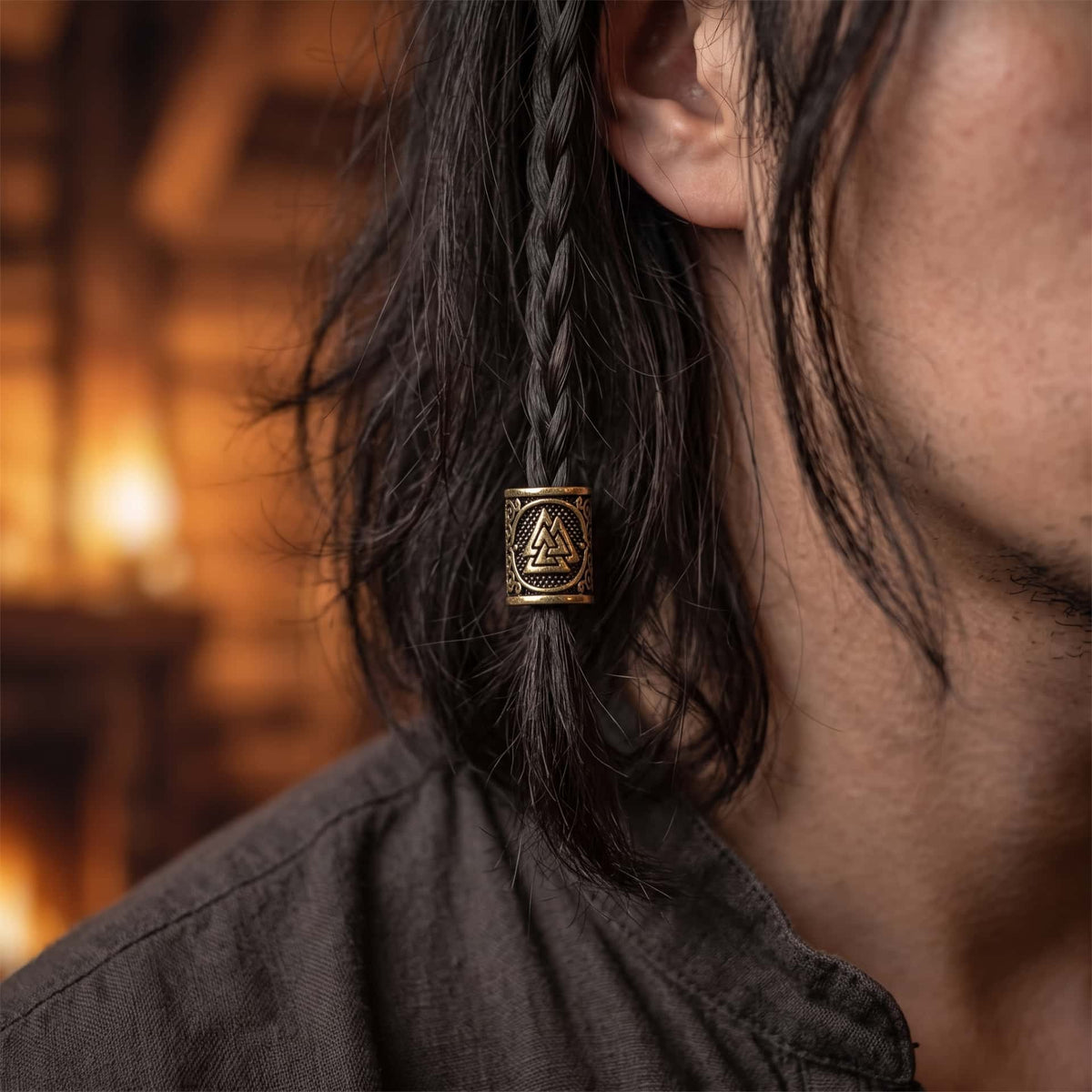 Perle viking en alliage bronze patiné, gravée du Valknut, trois triangles entrelacés dans un médaillon, portée sur une fine tresse de cheveux