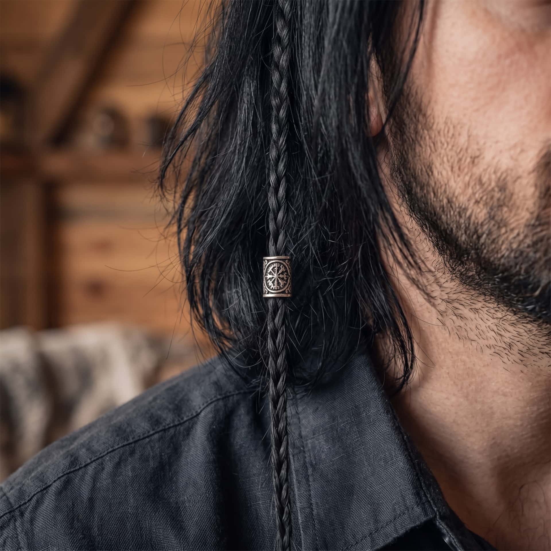 Perle viking en alliage argent vieilli, gravée du Vegvísir, dont les huit branches se terminent toutes différemment, portée sur une fine tresse de cheveux