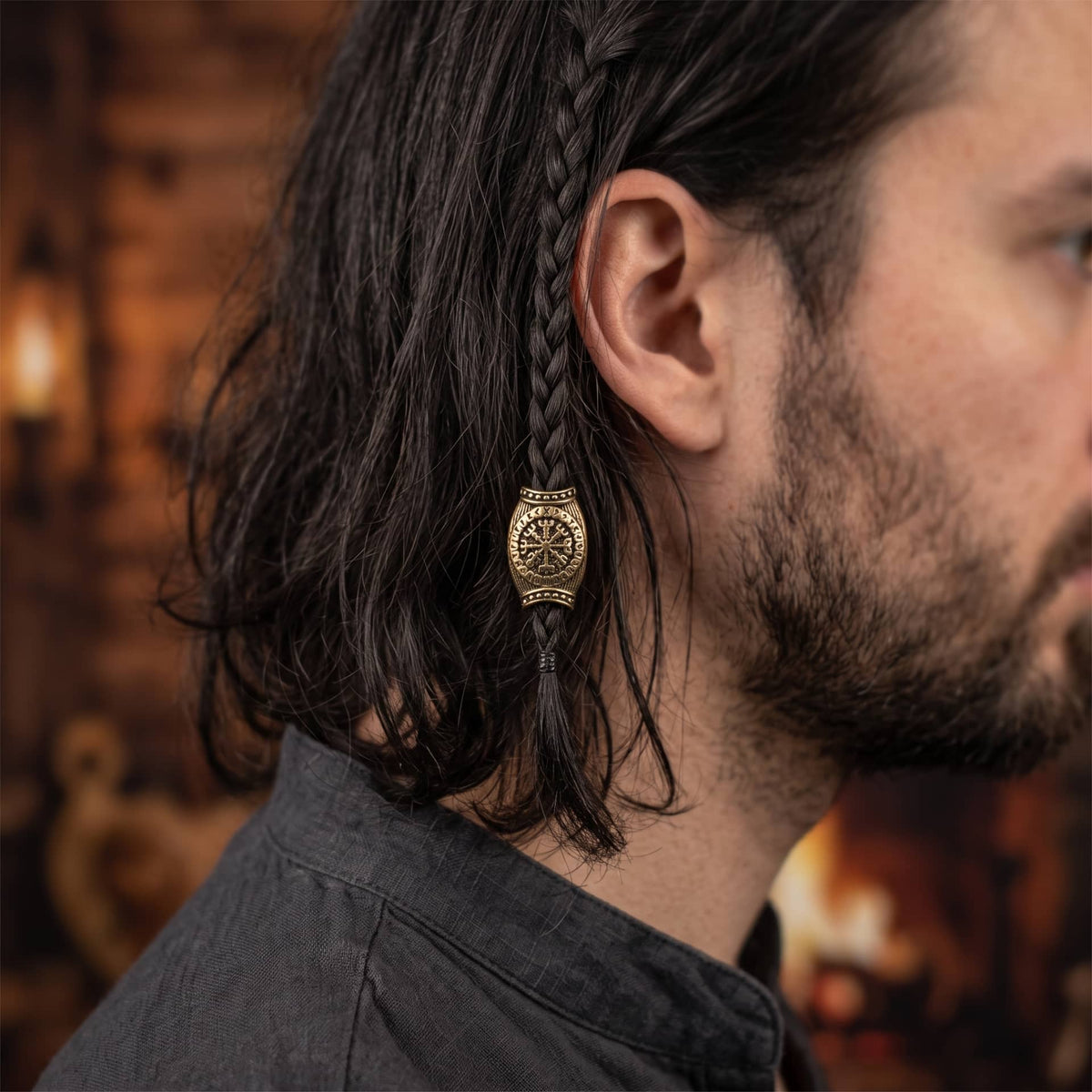 Perle viking en alliage bronze patiné, en forme de tonneau strié, Vegvísir cerclé d'un anneau de runes, portée sur une fine tresse de cheveux
